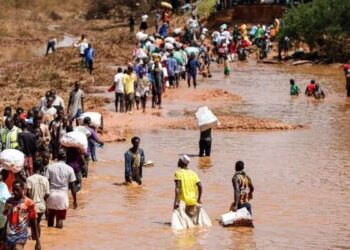 Orang-orang menyeberangi bagian yang hancur akibat banjir di Jalan Bangali-Garissa di Tana River County, Kenya, pada 1 Desember 2023.