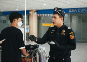 Petugas sedang memeriksa penumpang.