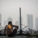 Kualitas Udara Jakarta Tidak Sehat, Terburuk Ketiga di Dunia 2 Seorang warga berjemur dengan latar belakang gedung bertingkat tersamar kabut polusi udara di Jakarta, Selasa (20/4/2021).