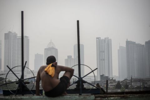 Kualitas Udara Jakarta Tidak Sehat, Terburuk Ketiga di Dunia 1 Seorang warga berjemur dengan latar belakang gedung bertingkat tersamar kabut polusi udara di Jakarta, Selasa (20/4/2021).