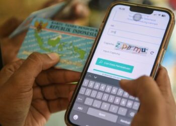 Warga mengecek nomor induk kependudukan (NIK) dengan ponselnya.