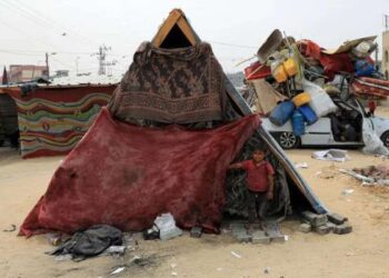 Seorang anak laki-laki Palestina berdiri dan melihat ke luar tenda di kamp sementara di kota Rafah, Jalur Gaza selatan, pada 10 Mei 2024.