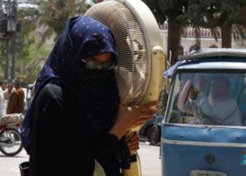 Seorang perempuan Pakistan membawa kipasnya menuju tempat reparasi di Karachi.