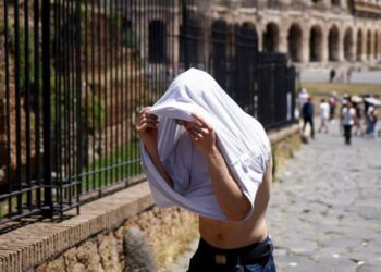 Seorang pria berlindung dari matahari dengan kaos di dekat Colosseum selama gelombang panas melanda Italia, di Roma, Italia.
