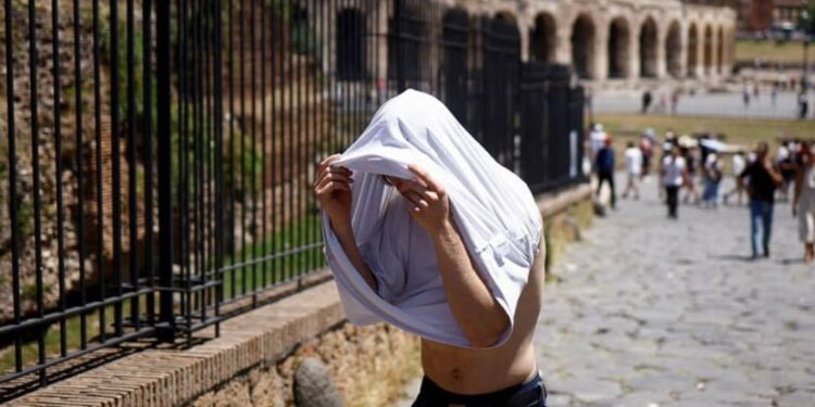 Seorang pria berlindung dari matahari dengan kaos di dekat Colosseum selama gelombang panas melanda Italia, di Roma, Italia.