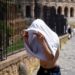 Gelombang Panas di Italia Tewaskan Lima Orang 2 Seorang pria berlindung dari matahari dengan kaos di dekat Colosseum selama gelombang panas melanda Italia, di Roma, Italia.