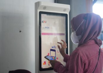 Penumpang sedang membeli tiket Melalui mandiri tiket box di stasiun.